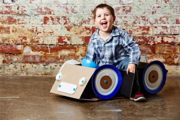 Niño jugando con coche construido con carton y makedo